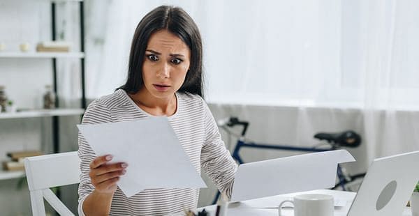 Woman staring at a paper while holding it with a shock on a her face.