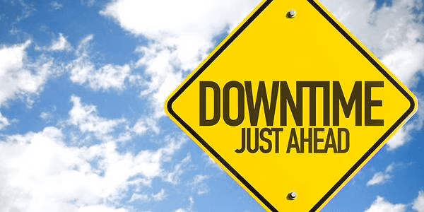 capitalized "Downtime Just Ahead" black text in a yellow signage with sky background