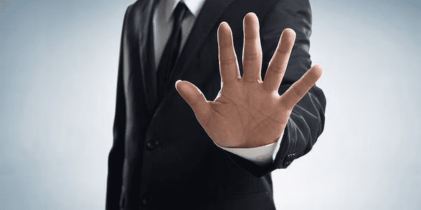 Man in a suit makes a hand raising gesture