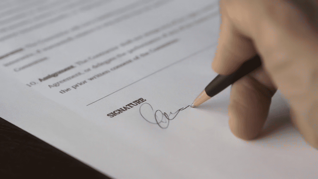 Signing of signature using a pen on a document.
