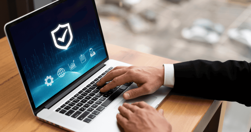A close-up of a person using a laptop featuring a glowing shield icon on the screen, representing the active maintenance of a secure and resilient online presence.