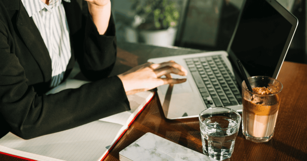 A person in a business suit works at a laptop with an open notebook and coffee nearby, reflecting a professional and comprehensive approach to digital management.