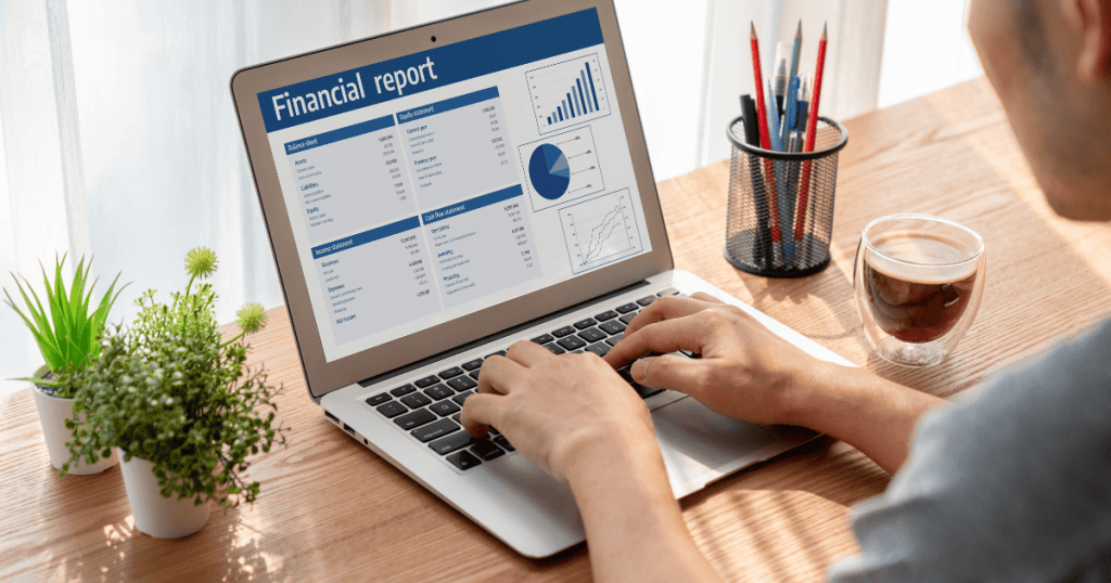 A person types on a laptop displaying a detailed financial report, capturing the analytical process of reviewing performance and earnings.