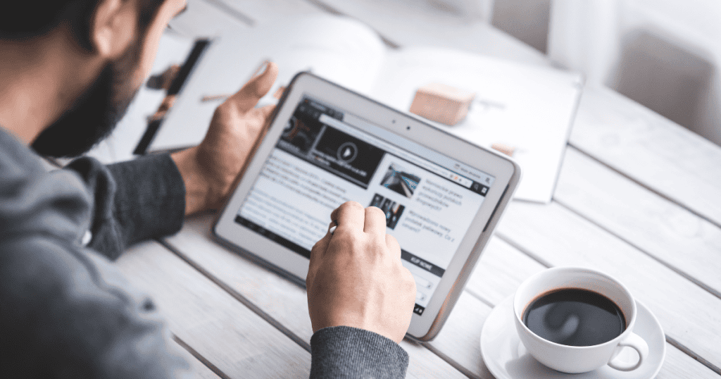 A man browses a website on a tablet while drinking coffee, illustrating the foundational elements that support a professional digital presence.