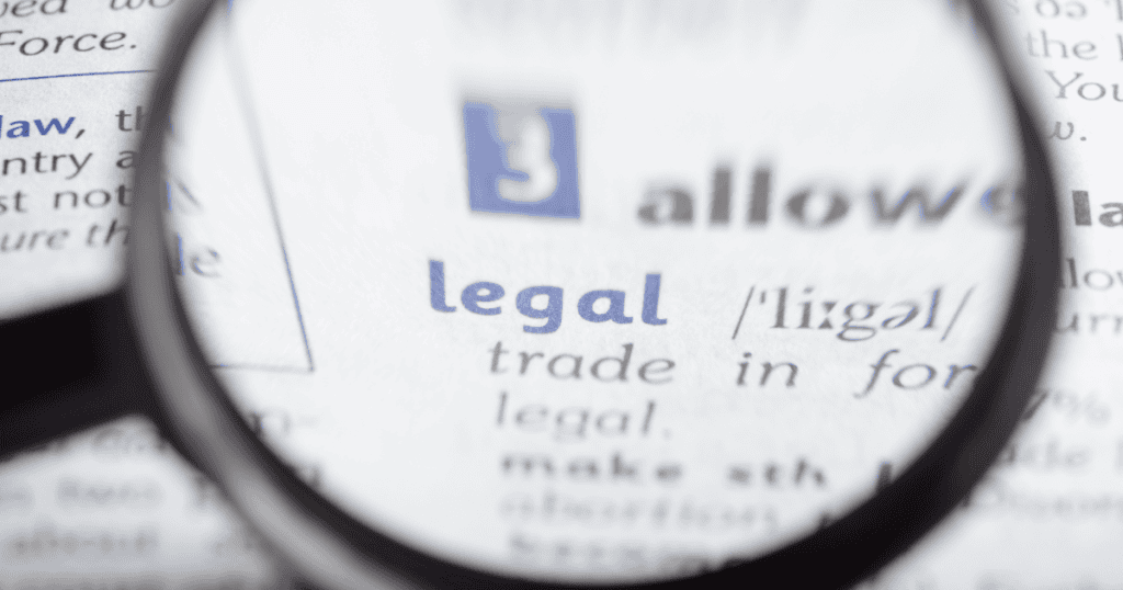 A magnifying glass zooms in on the dictionary definition of the word "legal," emphasizing the close scrutiny applied to a blog's regulatory compliance.