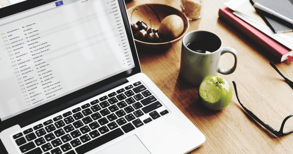 A laptop sits on a wooden table surrounded by snacks and a full email inbox, representing the various digital distractions that can be set aside during the early stages.