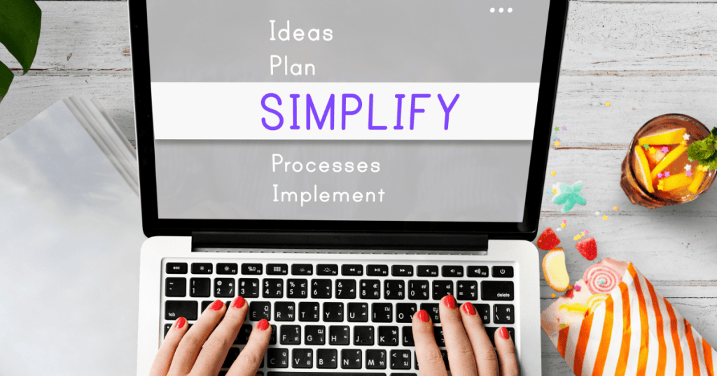 An overhead view of hands typing on a laptop displaying the word "SIMPLIFY," representing the process of distilling a brand identity down to its core.