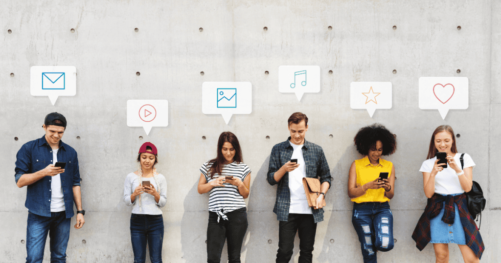 A diverse group of young adults stand against a concrete wall using their phones while distinct social media icons float above their heads, illustrating the varied digital interests of a target market.