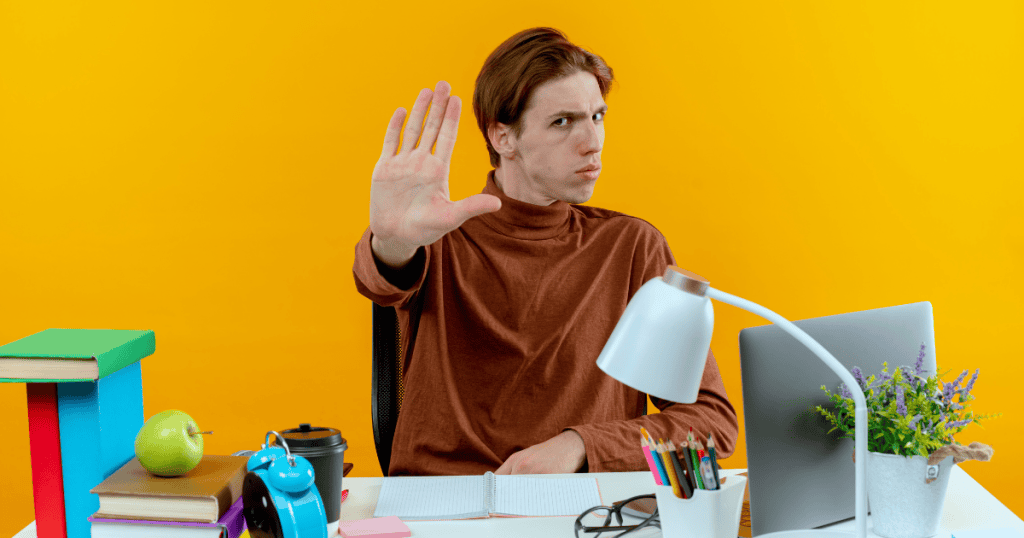 A man sitting at a desk and holding his hand up in a "stop" gesture, signaling a need to pause and address core structural errors.