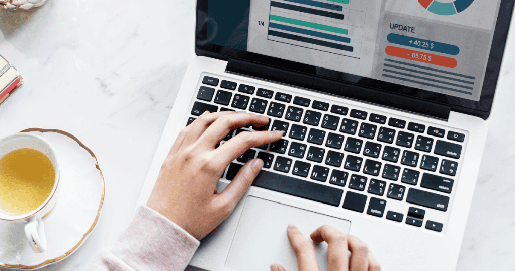 Close-up of hands typing on a laptop displaying data charts, capturing the process of tracking user interactions and metrics.