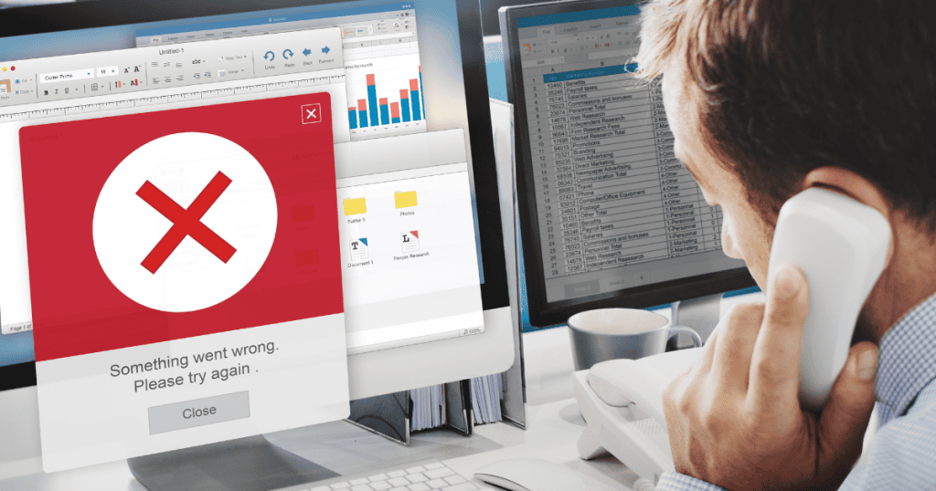 A man on the phone looking at a computer monitor covered in error messages and spreadsheets, illustrating the chaos of underlying system failures.