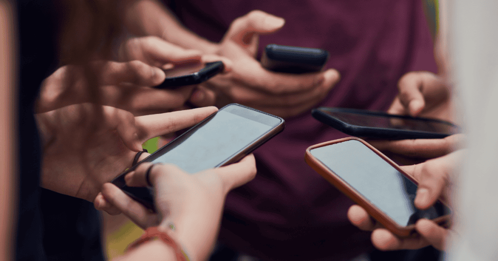 A close-up group of people holding and interacting with their smartphones, representing the missed connections in digital outreach.