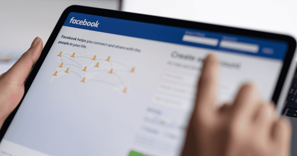 An out-of-focus view of a tablet screen showing the Facebook login page, highlighting the underlying platform mechanics that drive user engagement.
