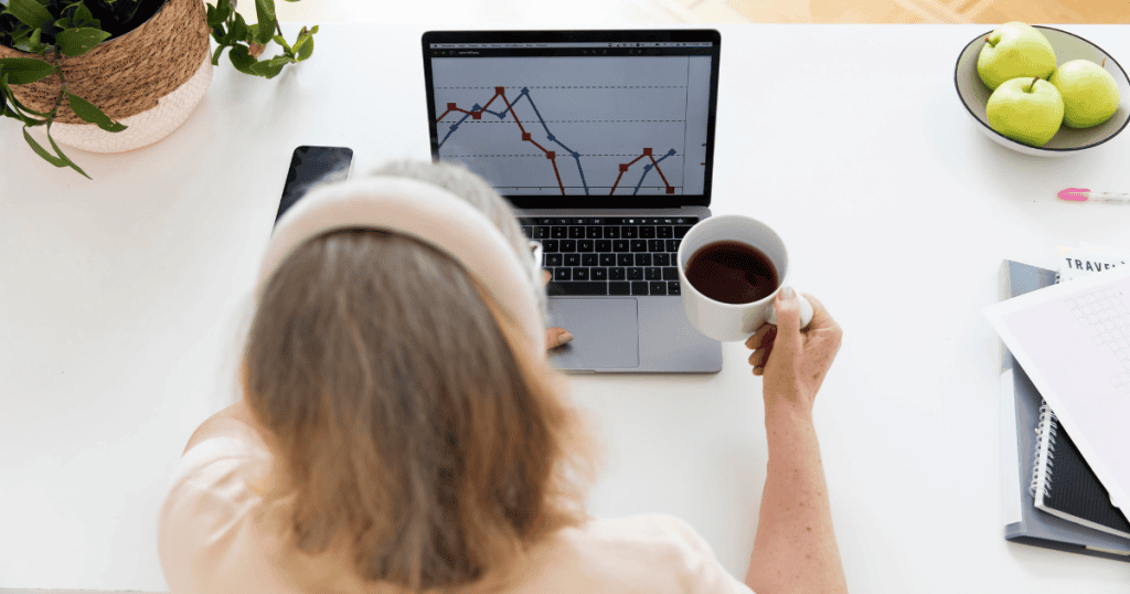 An overhead view shows a woman monitoring a fluctuating line graph on her laptop screen, depicting the visible impact that strategic choices have on overall performance.
