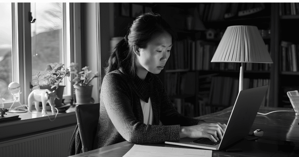 A focused woman works on her laptop in a dimly lit room, her concentrated gaze reflecting the precision needed to align a brand for profit.
