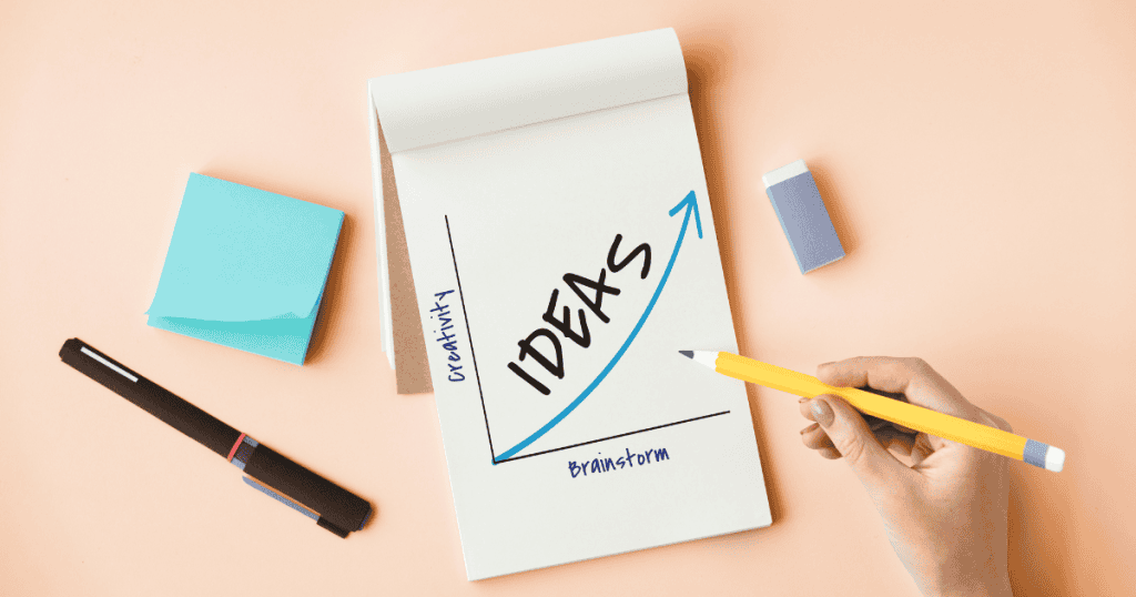 A hand draws an upward-trending arrow on a notepad labeled "IDEAS," illustrating the intentional path from brainstorming to creative growth.