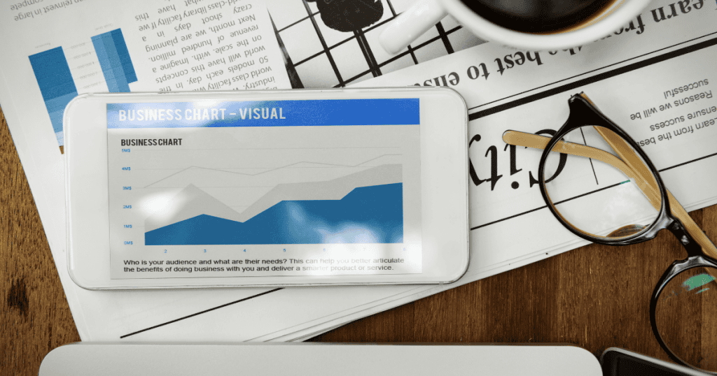 A smartphone displays a rising analytics chart next to a pair of glasses, highlighting a focused effort to understand and reach an audience.
