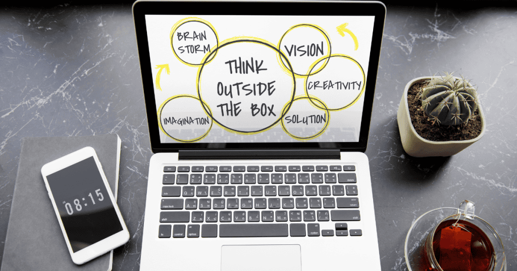 A laptop screen features a "Think Outside The Box" diagram surrounded by strategy bubbles, showcasing a more expansive and professional approach to problem-solving.