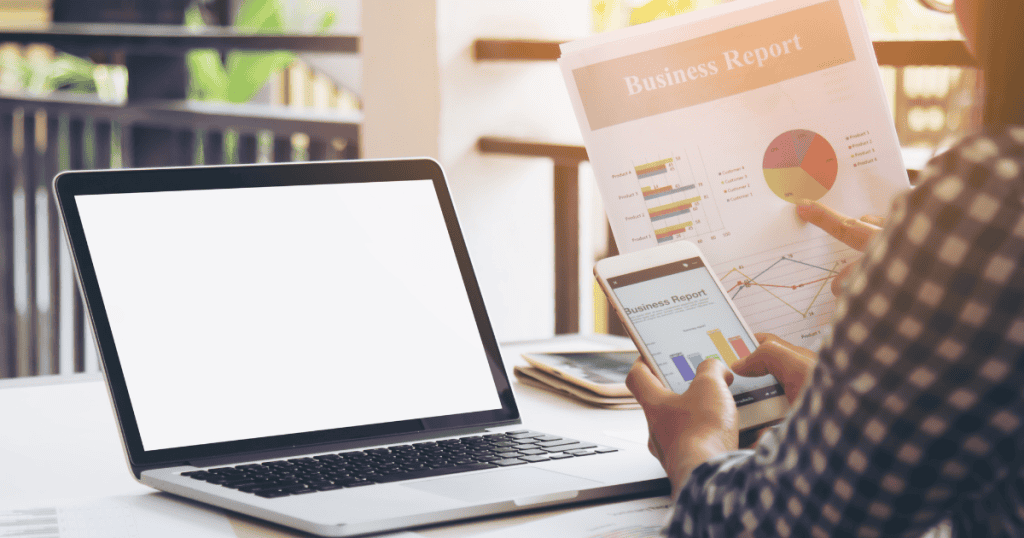 A person analyzes printed reports and mobile charts while sitting at a desk, marking the shift toward data-driven decision-making and accountability.